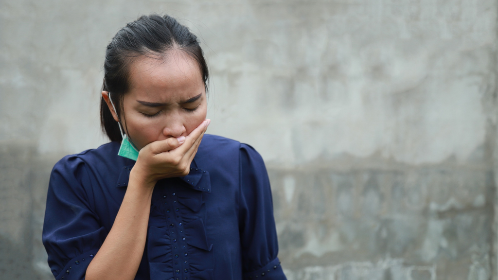 Woman covering her mouth while coughing